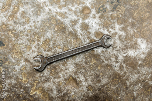 Old spanner on rumpled shabby metal, close-up abstract background © Aliaksei