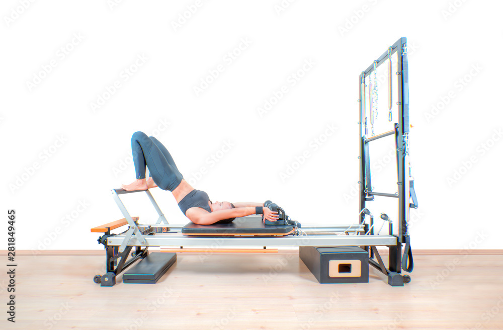 Fototapeta premium Young girl exercising on pilates reformers beds
