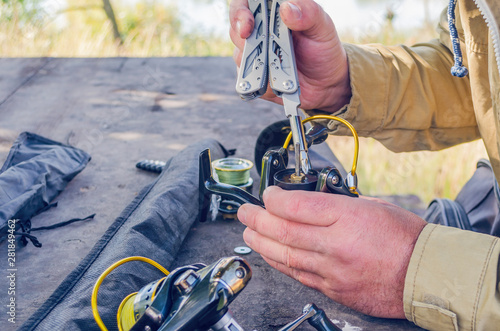 a man repairs a fishing reel with improvised means