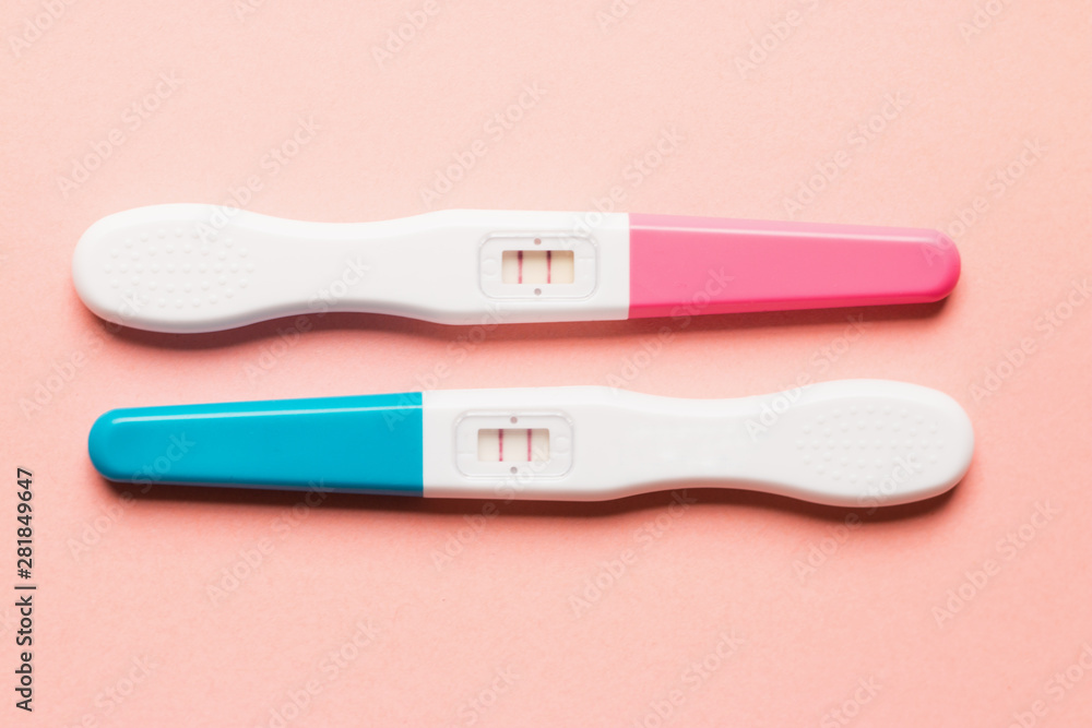 Positive pink and blue plastic pregnancy test on pink background Positive pink and blue plastic pregnancy test on pink background