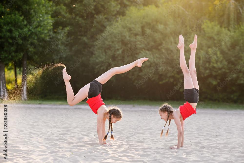 Sisters do gymnastics on the sand Sisters do gymnastics on the sand