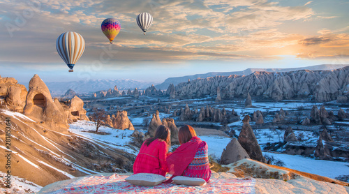 Fototapeta Naklejka Na Ścianę i Meble -  Hot air balloon flying over spectacular Cappadocia - Girls watching hot air balloon at the hill of Cappadocia