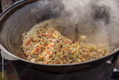 Cooking pilaf in a large cauldron on the street. Asian cuisine