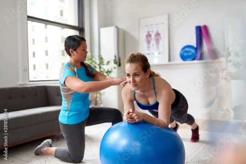 Chinese woman personal trainer during a workout session with an attractive blond client in a bright medical office