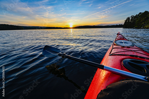 Fototapet red plastic kayak on calm water in the sunset