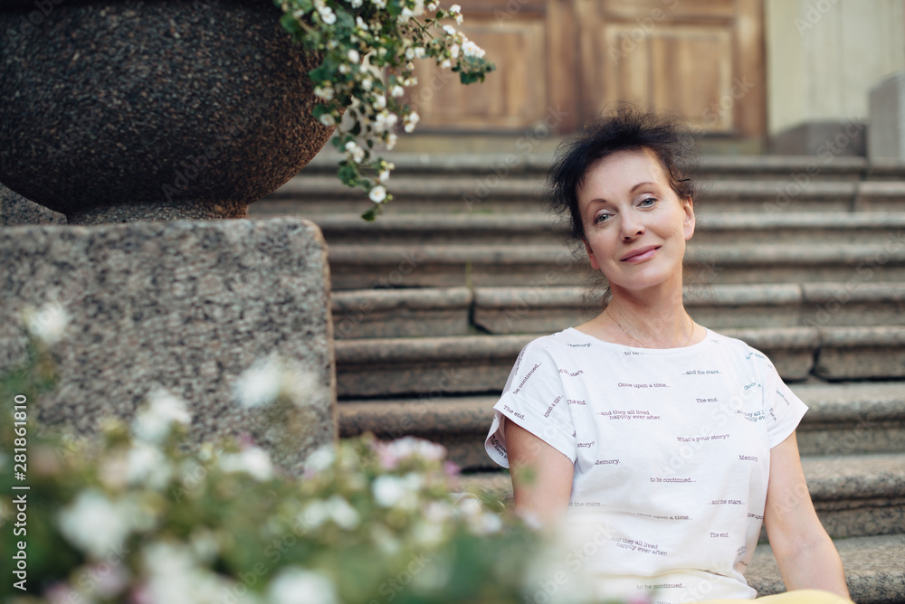 Fototapeta premium A beautiful tourist of Mature age sits on the steps in the city of St. Petersburg