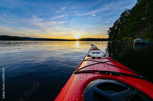 red plastic kayak on calm water in the sunset