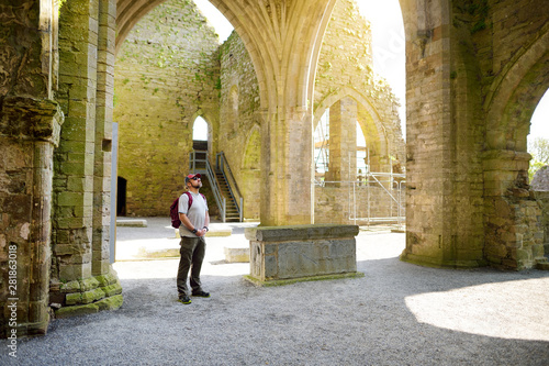Male tourist in Jerpoint Abbey, a ruined Cistercian abbey, located near Thomastown, County Kilkenny, Ireland. photo