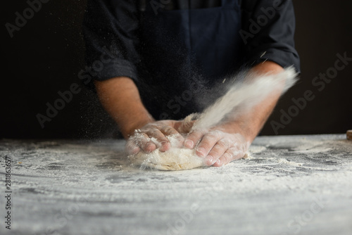 Fototapeta Naklejka Na Ścianę i Meble -  strong male hands knead the dough, the chef in the kitchen prepares pizza
