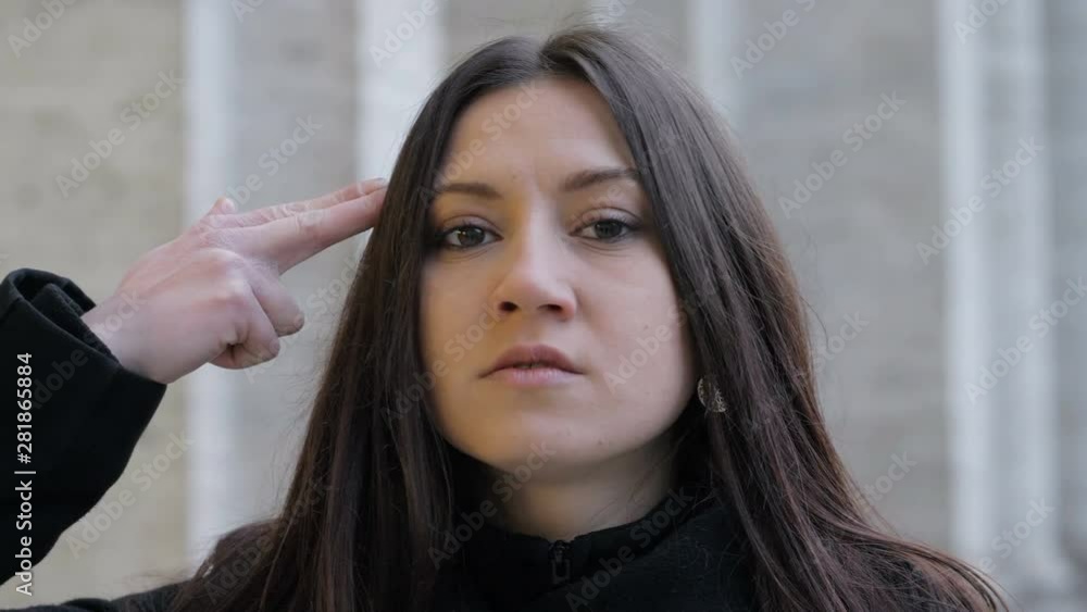 serious woman making the gesture of the gun to her head.concept,suicide- outdoor serious woman making the gesture of the gun to her head.concept,suicide- outdoor
