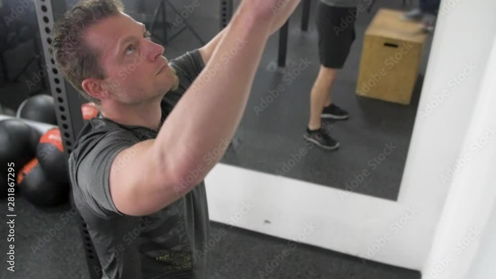 Athlete practicing wall ball shots with a med ball at the gym. Athlete practicing wall ball shots with a med ball at the gym.