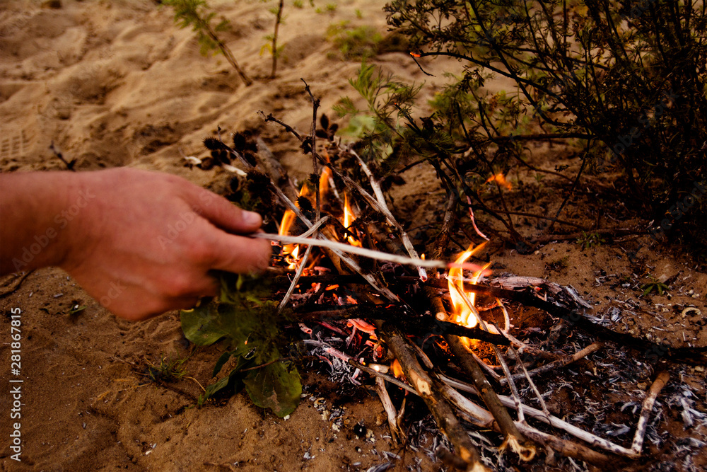 man makes a fire from branches in the forest man makes a fire from branches in the forest