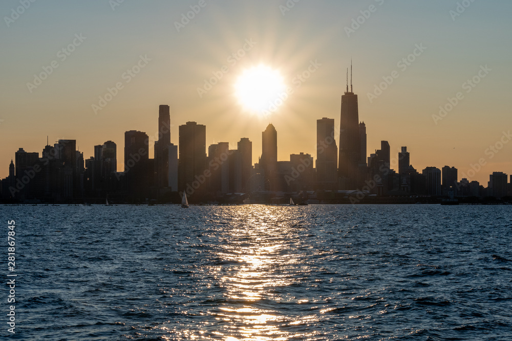 Chicago skyline sunset silhouette with sun reflecting off water in foreground (landscape)