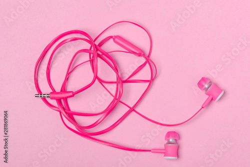 In-ear headphones on pink background © yuriygolub