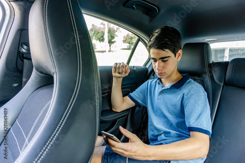 Young teenager with mobile sitting in luxury limousine.