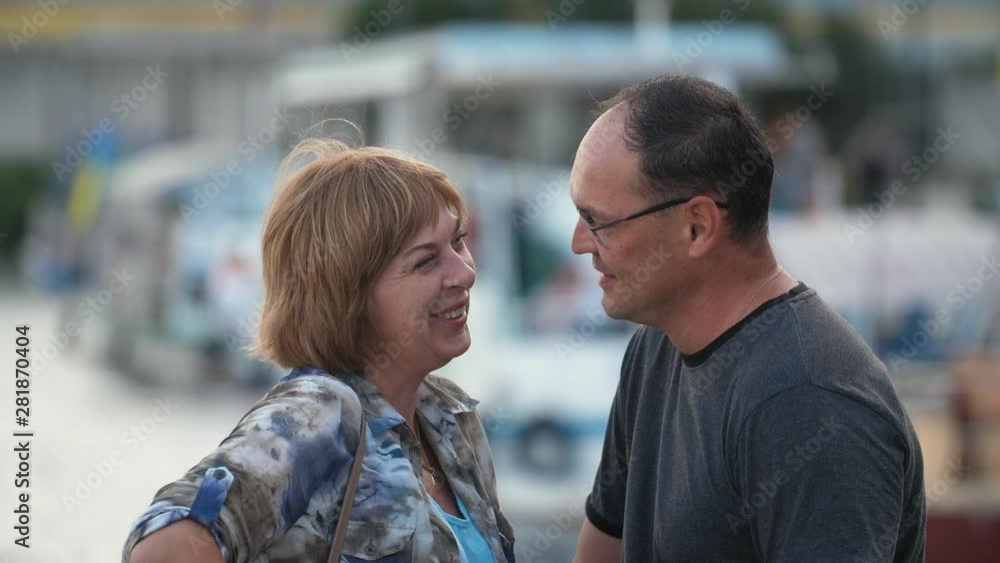 Positive adult couple talking outdoors on the quay in the evening, Close up Positive adult couple talking outdoors on the quay in the evening, Close up