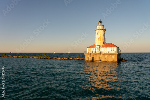 Chicago Harbor Lighthouse and breakwall at sunset with sailboats in background