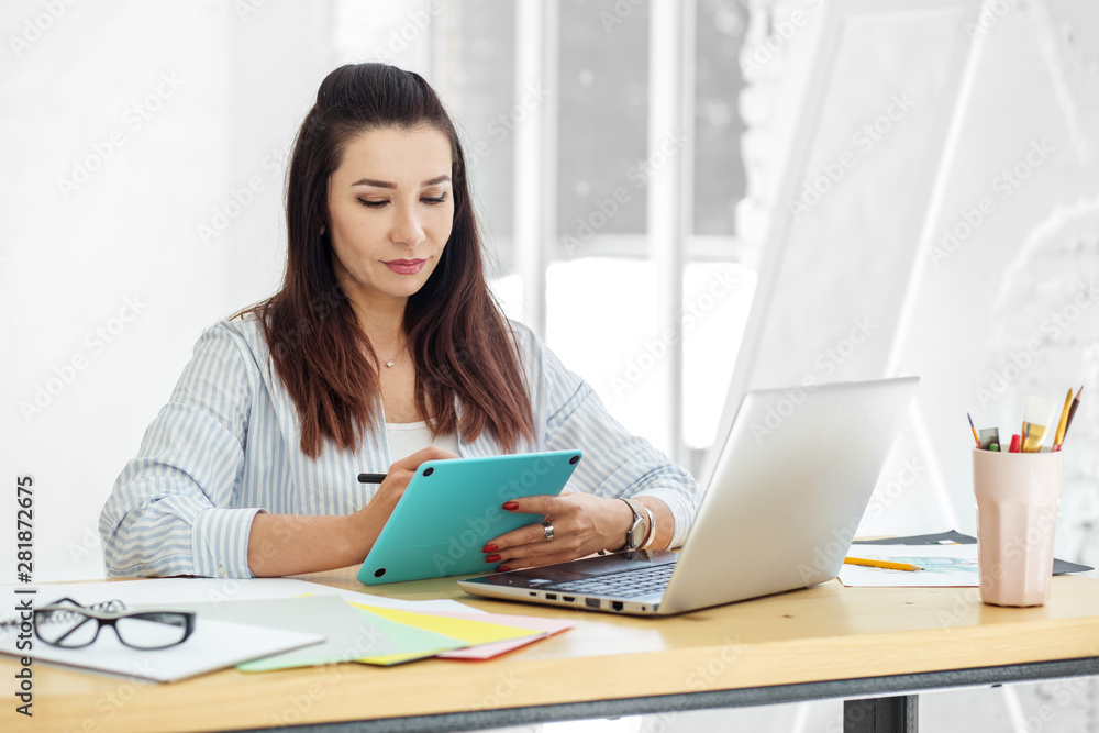Young illustrator draws on a tablet at work. Concept for business, work, career. Young illustrator draws on a tablet at work. Concept for business, work, career.