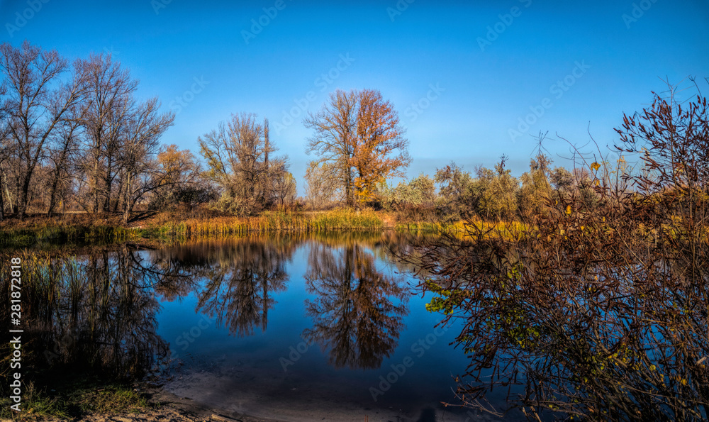 Beautiful autumn landscape. Trees reflected in the water of the lake	