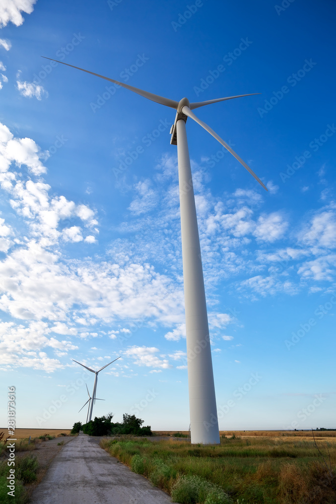 Wind turbines and agricultural field on a summer cloudy day. Energy production, clean and renewable energy. Wind turbines and agricultural field on a summer cloudy day. Energy production, clean and renewable energy.