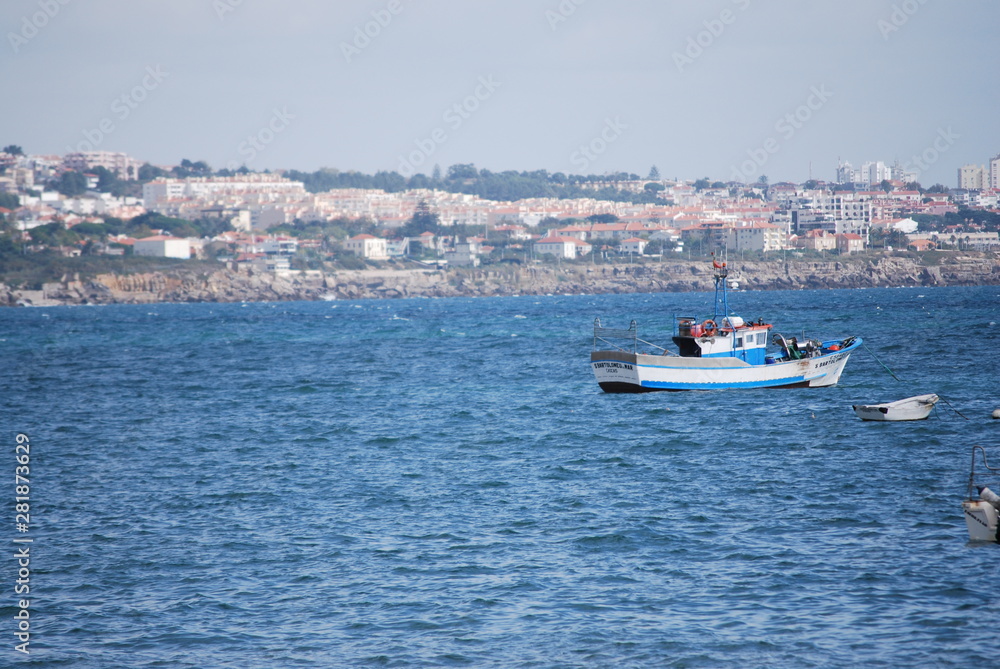 blue boat in the sea and city in the background