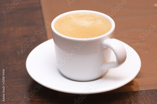 Fototapeta Naklejka Na Ścianę i Meble -  Closeup to white cup of espresso coffee on glass and wooden table 