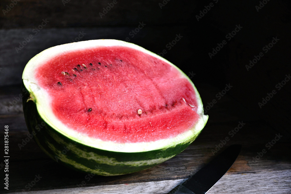 A watermelon cut in half, on an old rustic table. A watermelon cut in half, on an old rustic table.