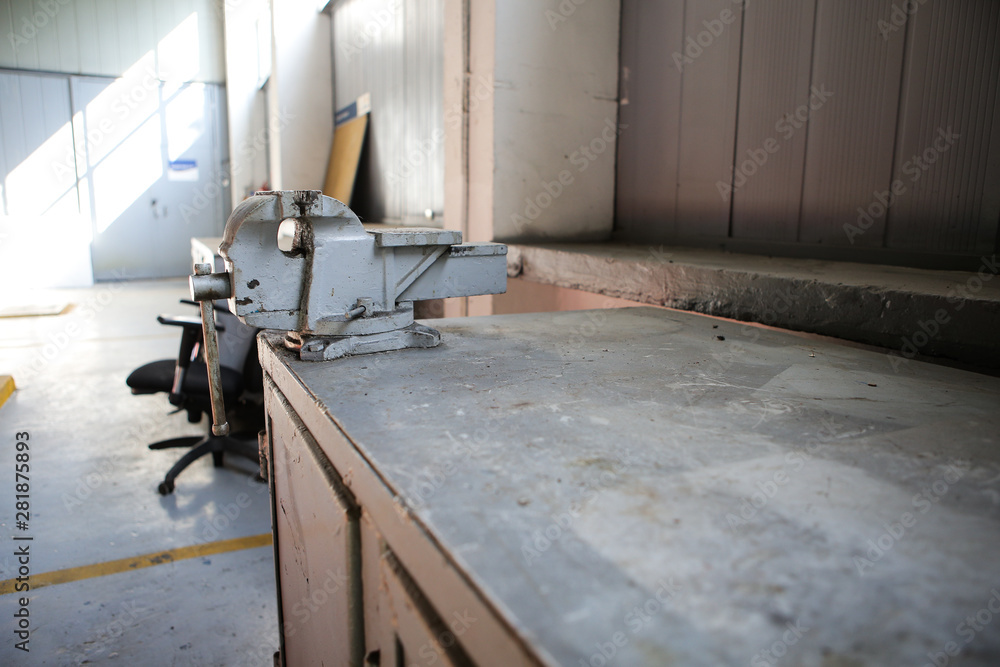 Shallow depth of field image with a rusty and dirty heavy iron vice on a workbench inside a workshop with no people around Shallow depth of field image with a rusty and dirty heavy iron vice on a workbench inside a workshop with no people around
