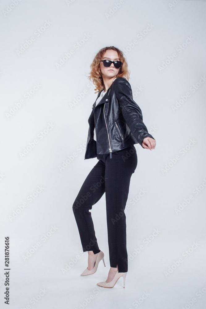 Pretty young fashion sensual woman posing on white background with dressed in hipster style leather jacket outfit. Stylish fashionable girl hipster in black clothes and white shirt. Pretty young fashion sensual woman posing on white background with dressed in hipster style leather jacket outfit. Stylish fashionable girl hipster in black clothes and white shirt.