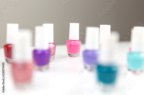 Group of bright multicolor assorted nail polishes on a white table