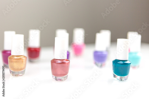 Group of bright multicolor assorted nail polishes on a white table