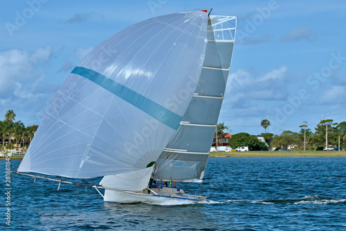 Children Sailing small sailboat boat with a white spinnaker on an inland waterway.