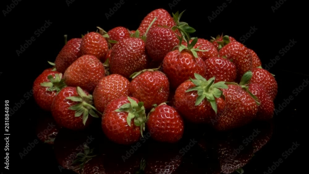 Rotation of juicy ripe strawberries with a mirror reflection from a glossy black surface. Rotation 360 degrees, closeup. 4K - 50fps Rotation of juicy ripe strawberries with a mirror reflection from a glossy black surface. Rotation 360 degrees, closeup. 4K - 50fps