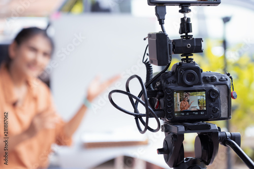 Young attractive Asian woman blogger looking at camera and talking on video shooting Video camera set record