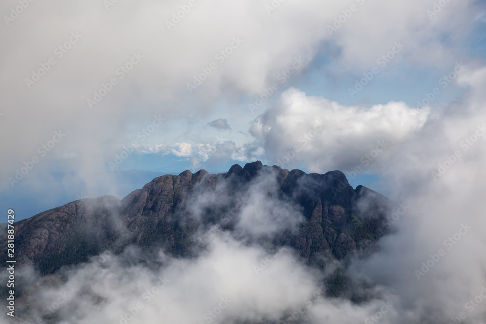 Fototapeta premium Aerial view of Mt Arrowsmith surrounded by clouds during a vibrant sunny summer day. Taken near Nanaimo and Port Alberni, Vancouver Island, British Columbia, Canada.