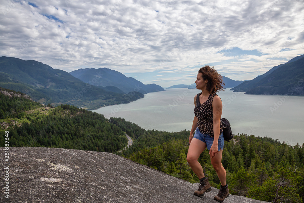 Naklejka premium Adventurous Girl Hiking up a mountain during a vibrant summer day. Taken in Murrin Park near Squamish, North of Vancouver, BC, Canada.