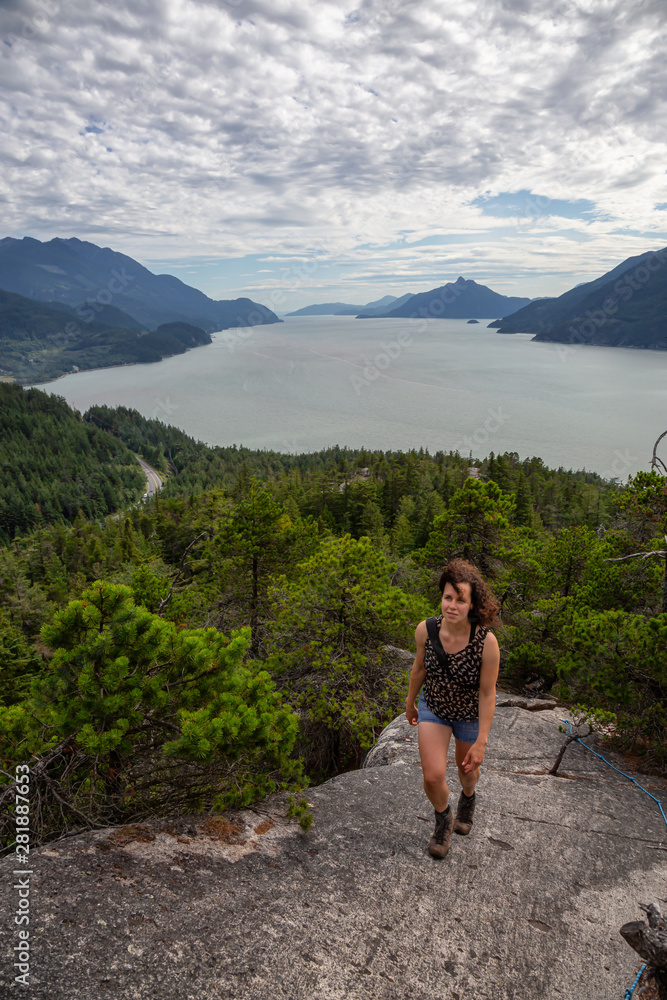 Naklejka premium Adventurous Girl Hiking up a mountain during a vibrant summer day. Taken in Murrin Park near Squamish, North of Vancouver, BC, Canada.
