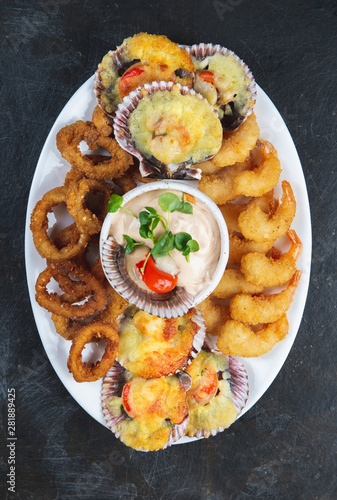PERUVIAN FOOD. Piqueo caliente. Hot seafood platter fried shrimps, squid rings and baked scallops with sauce 