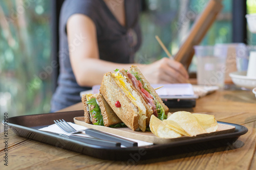 Club sandwich with bacon - chicken, fie egg, cheese, potato and lettuce on wooden tabel in cafe background. photo