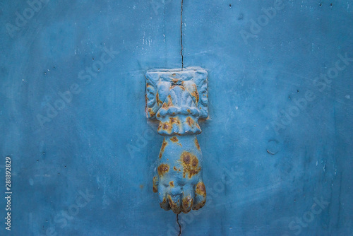 Vintage door knocker as women hand on the blue door