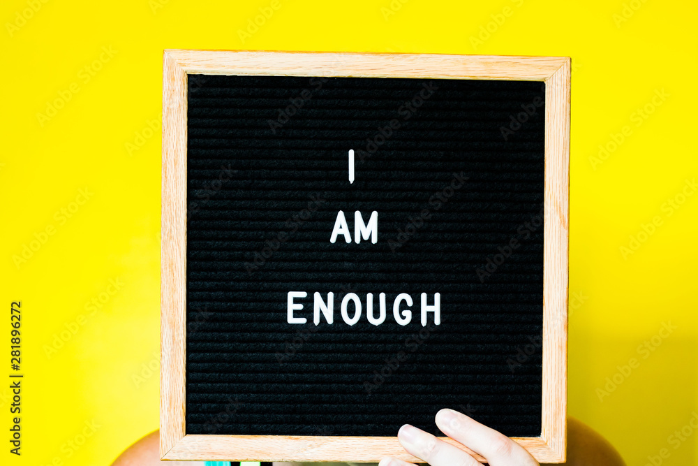 I Am Enough Written on a Letterboard on a Yellow Background