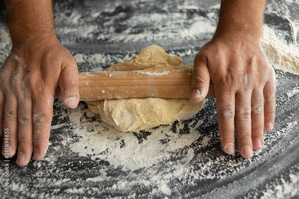 chef rolls out the dough with a rolling pin, ingredient for making pizza chef rolls out the dough with a rolling pin, ingredient for making pizza