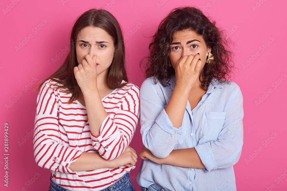 Close up shot of Caucasian girls pinching her nose to avoid bad smell, brunette women in aversion to awful stink, having negative emotions and nasty feelings, ladies wearing casually, look at camera. Close up shot of Caucasian girls pinching her nose to avoid bad smell, brunette women in aversion to awful stink, having negative emotions and nasty feelings, ladies wearing casually, look at camera.