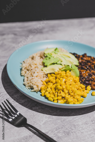 vegan mexican style dish with spicy black bean coconut rice corn and avocado