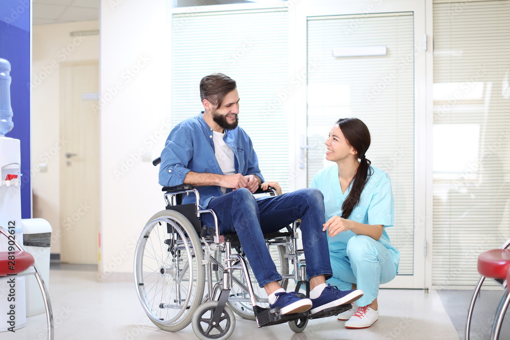 Young female doctor taking care of man in wheelchair indoors Young female doctor taking care of man in wheelchair indoors