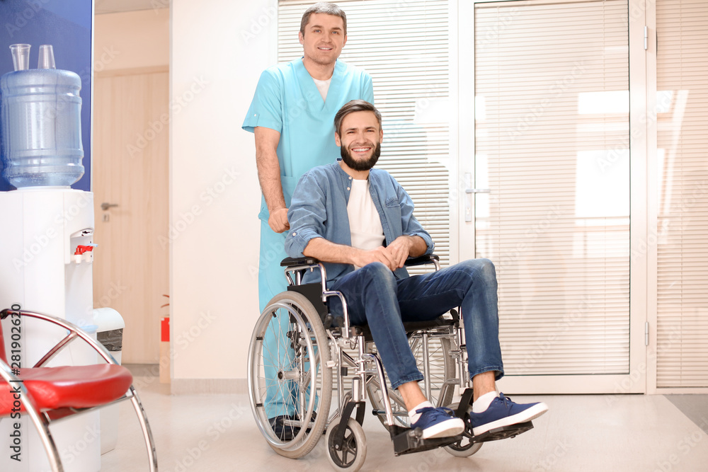 Male doctor taking care of man in wheelchair indoors Male doctor taking care of man in wheelchair indoors