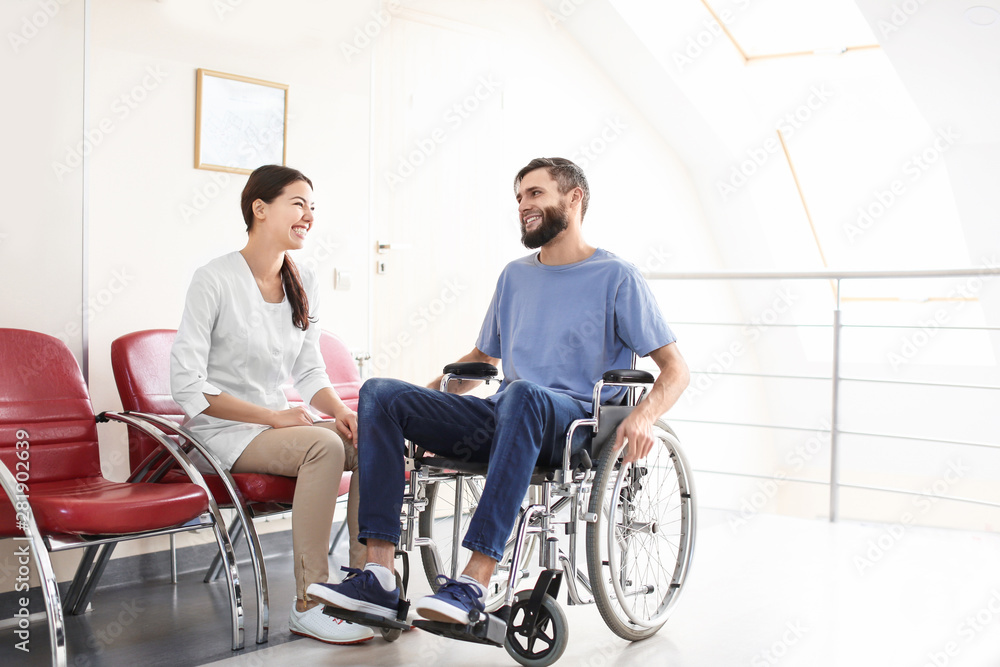 Young female doctor taking care of man in wheelchair indoors Young female doctor taking care of man in wheelchair indoors