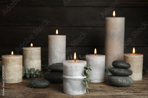 Composition with burning candles  spa stones and eucalyptus on wooden table