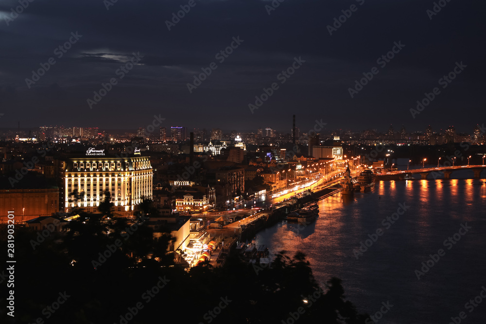 KYIV, UKRAINE - MAY 21, 2019: Beautiful view of night city with illuminated Fairmont Grand Hotel and other buildings near river