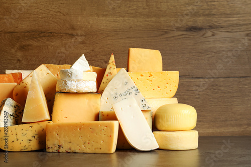 Different types of delicious cheese on table against wooden background